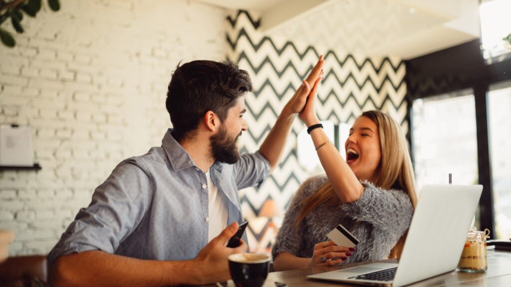 Couple celebrating in front of laptop