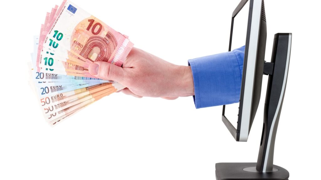 Hand coming from computer screen holding euros